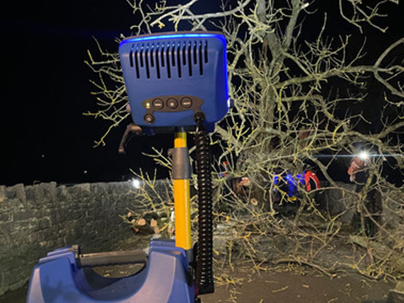 removing fallen tree at night time near stone wall with lights
