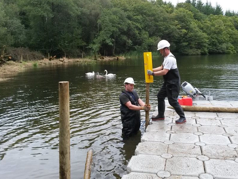 man on floating pontoon and man in water installing supports
