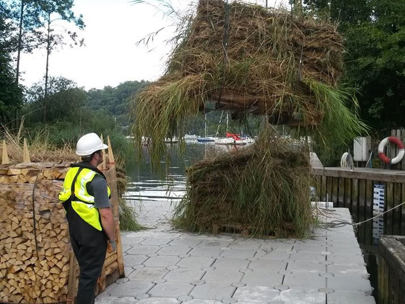 clearing river grass with crane onto floating pontoon